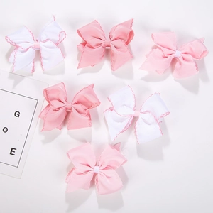 Close-up of six baby ribbon bow clips in pink and white with wave stitched edges