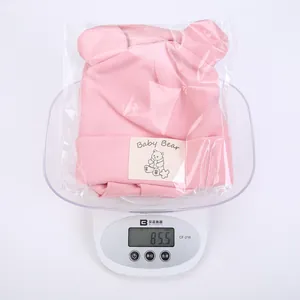 Detailed view of a pink knitted baby bear hat on a digital scale weighing 85.5 grams