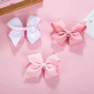 Close-up of pink and white ribbed ribbon bow hair clips with scalloped edges for girls