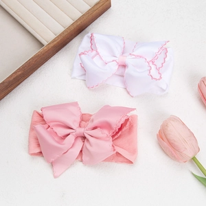 Close-up of pink and white soft nylon baby headbands with scalloped bow detailing