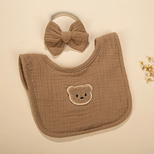 Detail of soft 4-layer cotton gauze baby bib with plush bear patch and matching bow headband