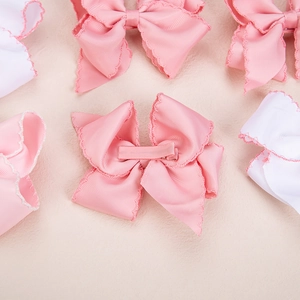 Close-up of pink and white bow hair clips with delicate red wavy scalloped edges