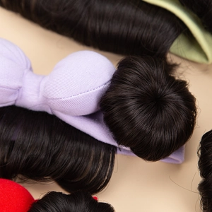 Macro shot of a soft lavender knitted baby headband with a realistic black hair bun detail