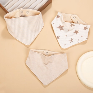 Détail de trois bavoirs en coton pour bébé avec texture douce et boutons-pression
