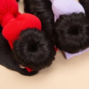 Close-up of black synthetic hair bun wig with red and purple fabric base for baby