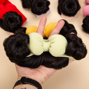 Detail showing baby double bun hair ring with a light green bow and synthetic hair texture