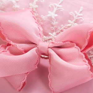 Macro shot of pink grosgrain ribbon bow hair clip with decorative scalloped edges