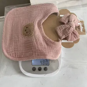 Pink cotton gauze baby bib and headband set with bear patch showing 48g weight