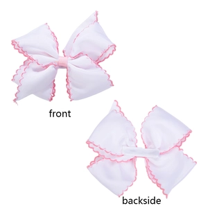 Front and backside view of white ribbon hair clips with pink scalloped edges for girls