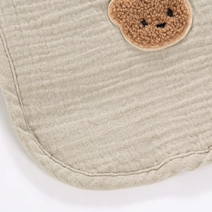 Macro detail of soft 4-layer cotton gauze baby bib with cute embroidered bear patch