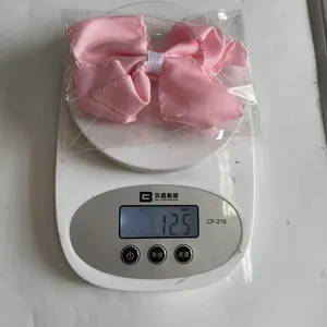 Detailed close-up showing a pink polyester bow hair clip weighing 12.5g on a digital scale