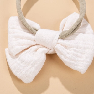 Detail of white cotton gauze baby bow headband with olive green elastic soft nylon strap