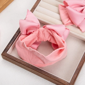 Soft nylon baby headband with a large pink bow, displayed in an elegant gift box