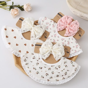 Détail d'un lot de bavoirs bébé avec bordure en dentelle et noeud décoratif sur coton
