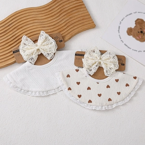 Détail d'un lot de bavoirs pour bébé avec nœud en dentelle et motifs de cœurs mignons
