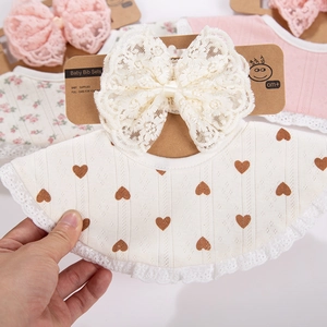 Vue détaillée de l'ensemble bavoir bébé et bandeau en dentelle avec cœurs et nœud