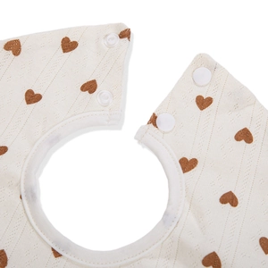 Gros plan d'un bavoir en coton pour bébé avec motifs de cœurs et boutons-pression blancs