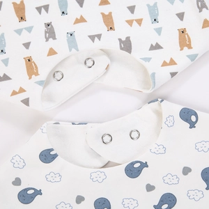 Close-up of baby cotton bibs with snap buttons and cute cartoon bear and whale prints