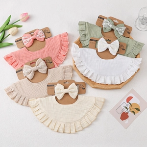 Detailed macro view of muslin cotton baby bib sets with ruffle edges and lace bows