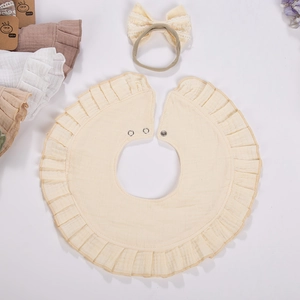 Close-up of beige 360-degree rotating ruffle bib with breathable gauze texture and snaps