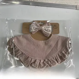 Detail of baby bib and headband set in dusty pink crepe cotton with lace and ruffles