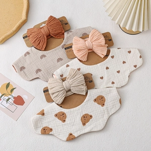 Three-piece baby bib and headband set featuring rainbow, heart, and bear patterns in warm tones