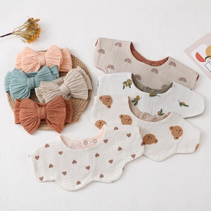 Detail of four organic cotton baby bibs and matching bow headbands on white texture