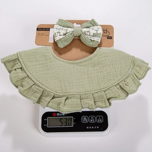 Close-up of sage green ruffled cotton bib and matching bow headband set for newborns