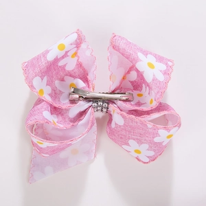 Détail d'une pince à cheveux nœud rose avec motif marguerite et clip crocodile argenté