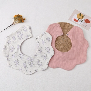 Detail of petal-shaped cotton muslin baby bibs with floral patterns and snap buttons