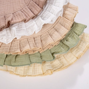 Detail view of ruffled cotton baby bibs in Morandi colors with soft muslin texture
