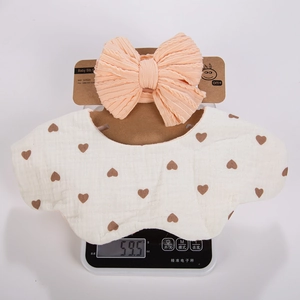 Close-up of heart print baby bib and bow headband set on a scale showing 59.5g weight