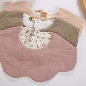 Close-up of soft cotton baby bibs with petal edges and floral prints in three colors