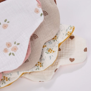 Detail of multi-layer soft cotton gauze baby bibs in floral and rainbow patterns