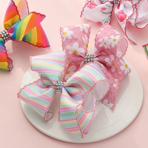 Nœuds à cheveux arc-en-ciel et marguerites avec strass sur une assiette blanche