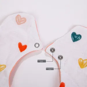 Detail of adjustable double snap buttons on a soft cotton baby bib with heart prints