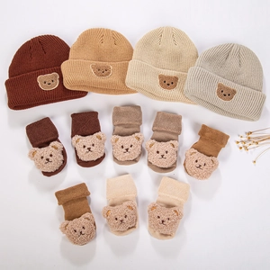 Detailed set of knit baby beanies and matching socks featuring plush bear decorations