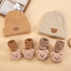 Close-up of baby knit hats and socks set with 3D teddy bear patches and embroidery