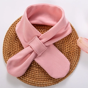 Soft pink knitted baby scarf with cross-loop design on a woven mat with tulip decor