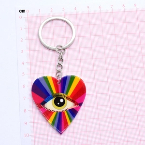 Rainbow evil eye heart keychain with colorful stripes and silver link chain on grid background