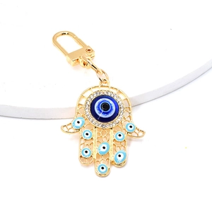 Detailed close-up of Hamsa Hand keychain with blue evil eye charms and gold finish