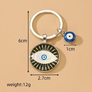 Silver Evil Eye keychain with blue glass pendant and bead charm on beige background