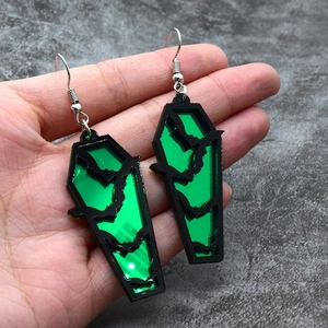 Close-up of green acrylic coffin earrings with black bat silhouette design details