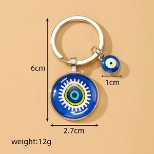 Retro evil eye keychain with blue glass pendant and metal ring on beige background