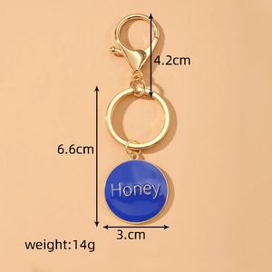 Detailed close-up of a gold Honey letter keychain with blue enamel heart pendant and clasp