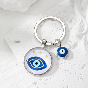 Macro detail of silver evil eye keychain with glass cabochon and blue bead pendant