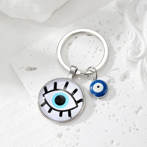 Detailed view of silver evil eye keychain with blue glass pendant on a stone background