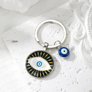 Detail of blue evil eye keychain with gold radial patterns on a textured white background