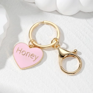 Close-up of pink heart keychain with Honey lettering and golden lobster clasp detail