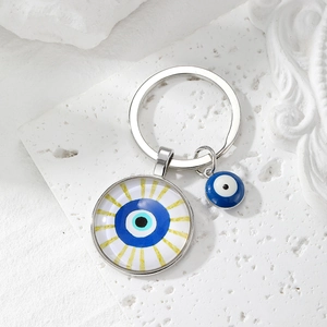 Blue Evil Eye keychain with glass eye pendants on a white stone textured background
